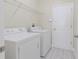 Bright laundry room features wood-look floors, appliances, storage shelf and a modern control panel at 20404 Autumn Fern Ave, Tampa, FL 33647