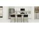 Modern kitchen with stainless steel appliances, island with seating, white cabinets, and adjacent laundry area at 2288 Blue Grosbeak Pl, Wimauma, FL 33598