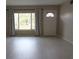 Bright living room features new flooring, a large window with curtains, and a white door, ready for personal touches at 2360 World Parkway Blvd # 36, Clearwater, FL 33763