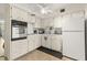 A corner view of an efficient kitchen, featuring white cabinets, a ceiling fan, and updated appliances at 2426 Persian Dr # 52, Clearwater, FL 33763