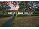 Charming exterior with well-manicured front yard, lush greenery, and warm, inviting lighting at dusk at 2880 81St N St, St Petersburg, FL 33710