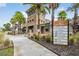 Community clubhouse entrance with stone accents, palm trees, and a welcoming sign at 32713 Brooks Hawk Ln, Wesley Chapel, FL 33543