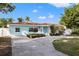Charming light blue home with a red tile roof, a well-manicured lawn, and mature landscaping at 3555 Belle Vista E Dr, St Pete Beach, FL 33706