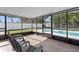 Enclosed lanai with seating area offering views of the backyard pool and lush landscaping at 3555 Belle Vista E Dr, St Pete Beach, FL 33706