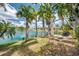 Lakeside backyard with mature palm trees offering tranquil waterfront views at 3558 65Th Avenue E Cir, Sarasota, FL 34243