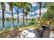 Backyard with palm trees offers serene lake views, a fire pit, and comfortable seating for outdoor enjoyment at 3558 65Th Avenue E Cir, Sarasota, FL 34243