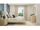 Bright bedroom featuring white bedding, a sunlit window with curtains, and a wooden dresser at 36017 Joseph Blake St, Zephyrhills, FL 33541