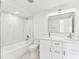 Bright bathroom featuring double vanity with marble countertop and a shower over tub with marble-look tile at 425 12Th Ave, Indian Rocks Beach, FL 33785