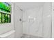 Bright bathroom featuring a tiled shower with niche, pebble flooring, and views of lush, tropical foliage at 425 12Th Ave, Indian Rocks Beach, FL 33785