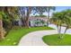 Lovely home featuring a long drive way, vibrant landscaping, palm trees, and unique architectural details at 425 12Th Ave, Indian Rocks Beach, FL 33785