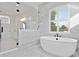 Stylish bathroom with a freestanding tub, frameless shower, and window with plantation shutters for natural light at 429 Erie Ave, Tampa, FL 33606