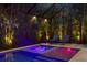 An inviting in-ground pool and spa are surrounded by tropical landscaping and illuminated by colorful lighting at 429 Erie Ave, Tampa, FL 33606