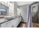 Bathroom with double sinks, modern faucets, dark countertops, and a walk-in shower with wood-like tiling at 4410 Foxboro Dr, New Port Richey, FL 34653