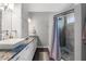 Bathroom featuring double sinks, white cabinetry, a tiled countertop, and a shower with a wood-like finish at 4410 Foxboro Dr, New Port Richey, FL 34653