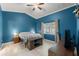 Bedroom featuring blue walls, neutral-toned bedding, and natural light from the window at 4410 Foxboro Dr, New Port Richey, FL 34653