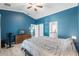 Bedroom showcasing blue walls, light flooring, a ceiling fan, and easy access to an attached bathroom at 4410 Foxboro Dr, New Port Richey, FL 34653