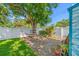 Backyard featuring a relaxing hammock under a large tree, with white fence and landscaped gravel area at 4721 W Lawn Ave, Tampa, FL 33611