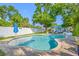 Serene backyard featuring a freeform pool, lush lawn, privacy fence, and cozy lounge area for relaxation at 4721 W Lawn Ave, Tampa, FL 33611