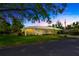 A charming single-story home boasts a manicured lawn, flowering bushes, and a metal roof beneath a picturesque sky at 509 N Walker St, Plant City, FL 33563