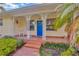 Inviting front porch with decorative columns, tile flooring, a bright blue front door, and lush landscaping at 509 N Walker St, Plant City, FL 33563