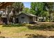 A cozy backyard with a view of the house, showing green grass and mature trees providing shade at 5421 Gay St, Weeki Wachee, FL 34607