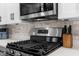 Kitchen with gray and white cabinets, stainless steel stove and microwave, with tile backsplash and modern design at 5421 Gay St, Weeki Wachee, FL 34607