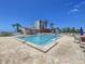 Brightly lit community pool is surrounded by lounge seating and tropical landscaping with a high-rise building in the background at 6290 Bahia Del Mar Cir # 12, St Petersburg, FL 33715