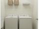 Functional laundry room with side-by-side washer and dryer, complemented by overhead shelving and storage at 6909 E 116Th Ct, Palmetto, FL 34221