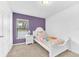 Bright bedroom with carpet flooring, neutral and purple paint, and a nice sized window at 7099 Crested Orchid Dr, Brooksville, FL 34602