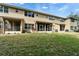 A view of the back exterior with a large lawn area, screened in porch and patio at 8132 Stone Path Way, Tampa, FL 33647