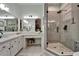 Bright bathroom featuring dual sinks, quartz counters, a vanity area, and a glass enclosed shower at 8132 Stone Path Way, Tampa, FL 33647