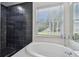 Modern bathroom showcasing a black tiled shower and a soaking tub overlooking a window at 8208 Pinewood Run Ct, Tampa, FL 33647