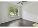 Cozy bedroom with dark wood floors, ceiling fan and a bright window with a view of the neighborhood at 8208 Pinewood Run Ct, Tampa, FL 33647