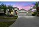 Beautiful home featuring a three-car garage, stone accents, and lush tropical landscaping at 8208 Pinewood Run Ct, Tampa, FL 33647
