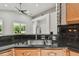 Black granite counters in a kitchen featuring a stainless steel sink, and wood cabinets at 8208 Pinewood Run Ct, Tampa, FL 33647