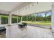 Screened lanai featuring a pallet-style seating area and serene views of the pond and backyard at 8208 Pinewood Run Ct, Tampa, FL 33647