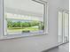 A large window view into the screened-in lanai, overlooking a grassy yard and pond at 8208 Pinewood Run Ct, Tampa, FL 33647