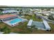 An aerial shot displays the community pool, shuffleboard courts, gazebo, and nearby lake and residential area at 9743 36Th N Way # 4, Pinellas Park, FL 33782