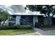 Condo's exterior showcasing the front entrance, mature trees, a partial lawn, and lush landscaping at 11201 122Nd Ave # 103, Largo, FL 33778