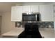 Kitchen featuring updated appliances, white cabinetry, and blue accent backsplash at 11201 122Nd Ave # 103, Largo, FL 33778