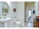 Well-lit bathroom features a pedestal sink, toilet, and doorway leading to a patio at 11205 Lark Landing Ct, Riverview, FL 33569