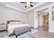 Bright main bedroom with tray ceiling, ceiling fan, a gray upholstered bed and bench, and entry to a hallway at 11205 Lark Landing Ct, Riverview, FL 33569