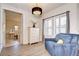 Sitting room with blue chair, chandelier, shutters, view into primary bathroom, and neutral walls at 11205 Lark Landing Ct, Riverview, FL 33569