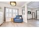 Cozy room with blue armchair, chandelier, neutral walls, shutters, and view into the primary bedroom at 11205 Lark Landing Ct, Riverview, FL 33569