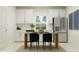 Bright kitchen with white cabinets, stainless steel appliances, and a wooden dining table with stylish blue chairs at 11837 Blue Diamond Trl, Parrish, FL 34219