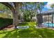 Spacious backyard with green turf, a screened-in lanai, a trampoline with a basketball hoop, and a hanging swing at 1207 S Druid Ln, Tampa, FL 33629