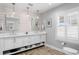 Bright bathroom with double vanity, white cabinets, wood plank accent wall and floors, and window with shutters at 1207 S Druid Ln, Tampa, FL 33629