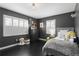 Dark and cozy bedroom featuring 2 windows with white shutters, dark wood floors, and accent furniture at 1207 S Druid Ln, Tampa, FL 33629