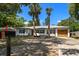 Charming single-story home featuring a minimalist design, palm trees, and a modern, light wood garage door at 14 S Meteor Ave, Clearwater, FL 33765