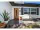 Inviting front porch with a stylish wood door, modern black accents, and potted plants at 14 S Meteor Ave, Clearwater, FL 33765